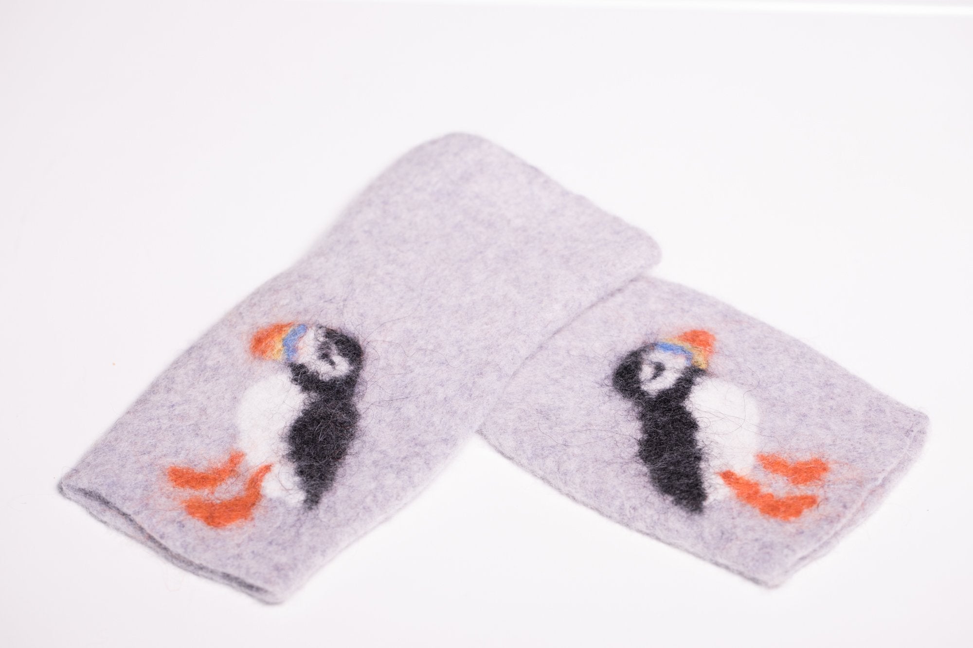 Warm and soft fingerless half mittens with a hand felted little puffin. Colour light grey.